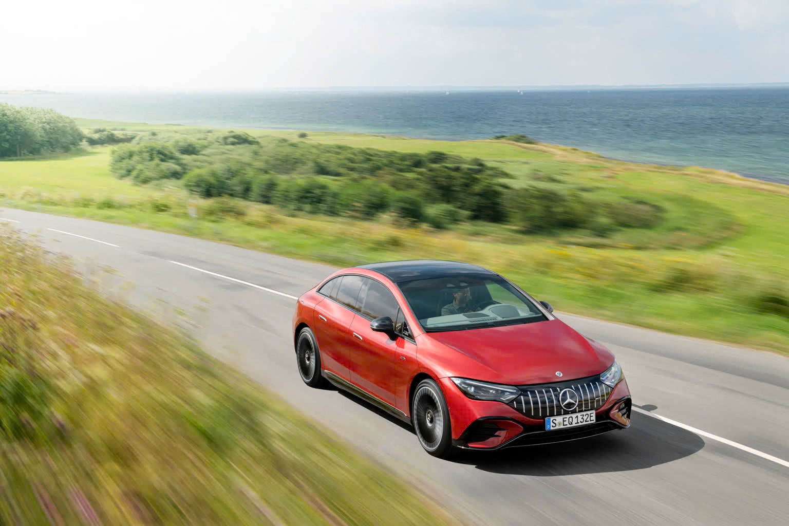 2025-2026-mercedes-amg-eqe-in-red-front-angled-view-driving.jpg